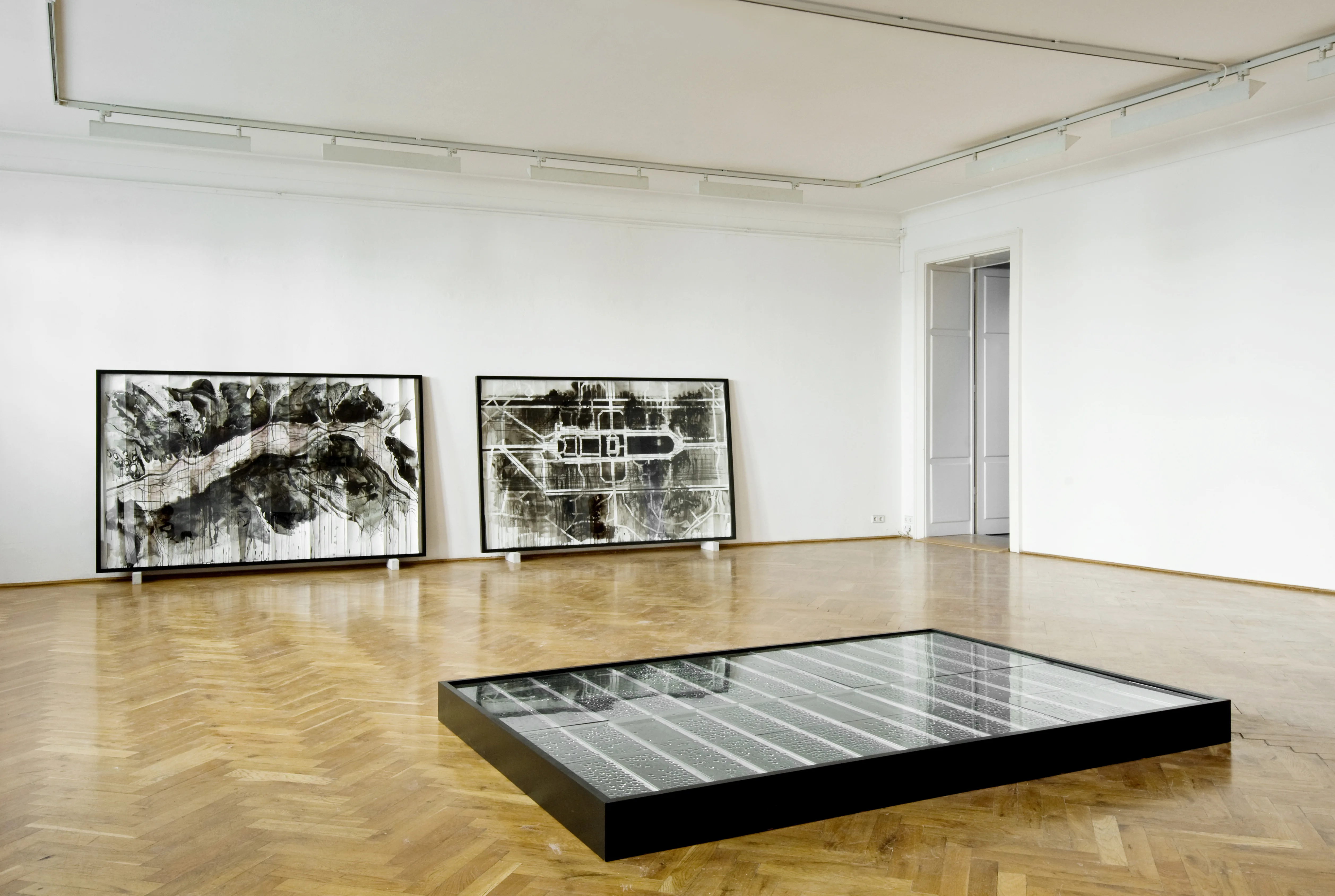 Ausstellungsansicht Kunsthaus Dresden 2013 — die Bodeninstallation Kondensat I als gerahmtes Glasfeld auf dem Parkett, an der Wand die Tuschezeichnungen Karte PG und Karte GG